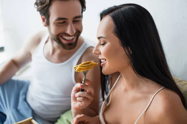 Homem alegre alimentando namorada com panquecas saborosas — Fotografia de Stock