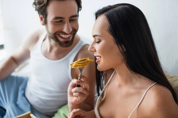 Uomo allegro che alimenta la ragazza con gustosi pancake — Foto stock