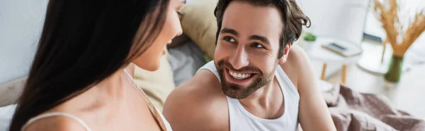 Femme floue et joyeuse regardant petit ami heureux au lit, bannière — Photo de stock