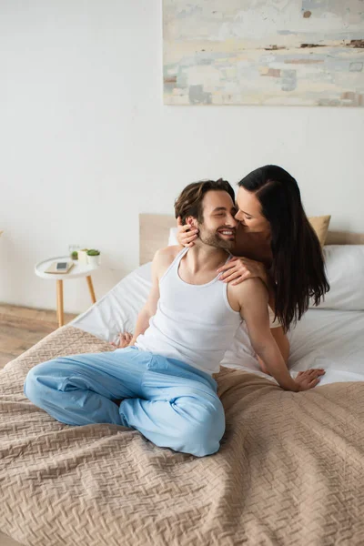 Happy girlfriend hugging cheerful boyfriend in bedroom — Stock Photo