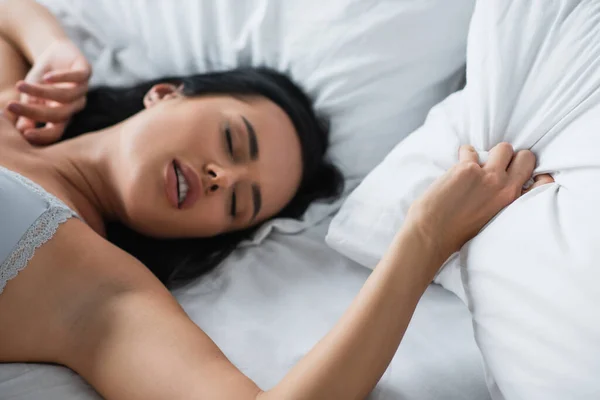 Young woman in sexy bra feeling pleasure on bed — Stock Photo