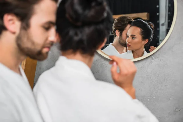 Reflection in mirror of young couple in white bathrobes — Stock Photo