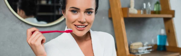 Cheerful young woman in white bathrobe brushing teeth, banner — Stock Photo