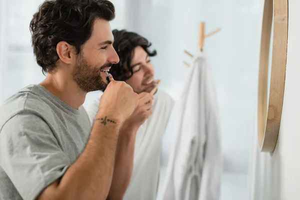 Улыбающаяся пара геев чистит зубы в ванной — стоковое фото