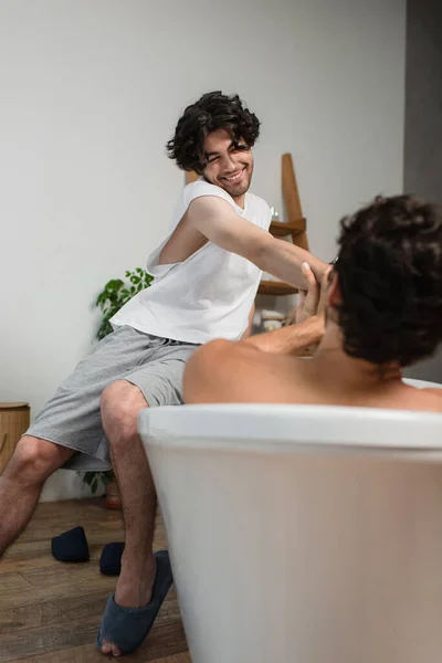 Felice gay uomo sorridente vicino offuscata fidanzato in vasca da bagno — Foto stock