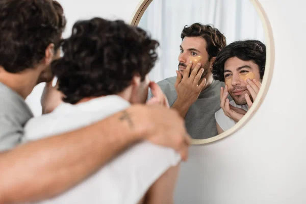 Bearded gay couple applying eye patches in bathroom — Stock Photo