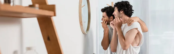 Heureux gay couple application eye patches dans salle de bain, bannière — Photo de stock