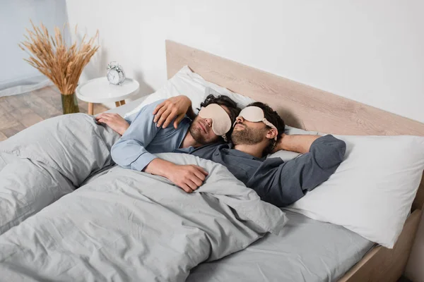 Гей пара в масках для глаз спит в постели — стоковое фото
