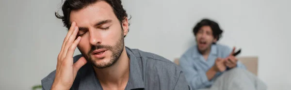 Man suffering from headache while quarrelling with boyfriend, banner — Stock Photo