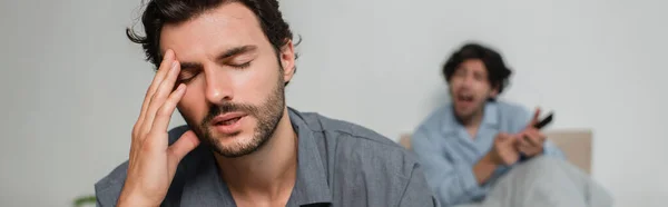 Homme souffrant de maux de tête tout en se querellant avec petit ami, bannière — Photo de stock