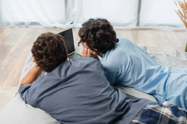 Indietro vista di gay coppia guardando film su laptop in letto — Foto stock