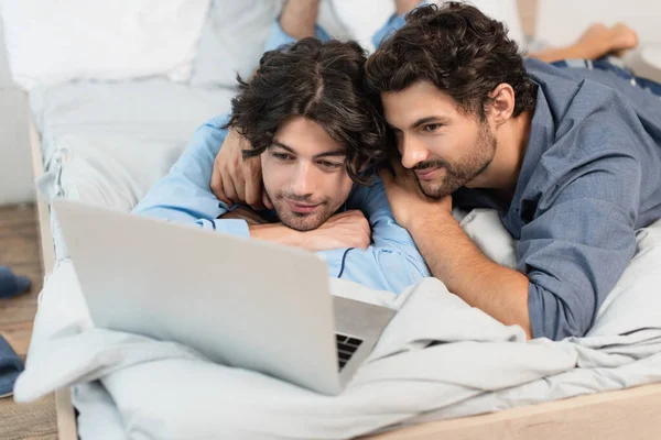 Lächelnd gay paar beobachten film auf laptop im schlafzimmer — Stockfoto