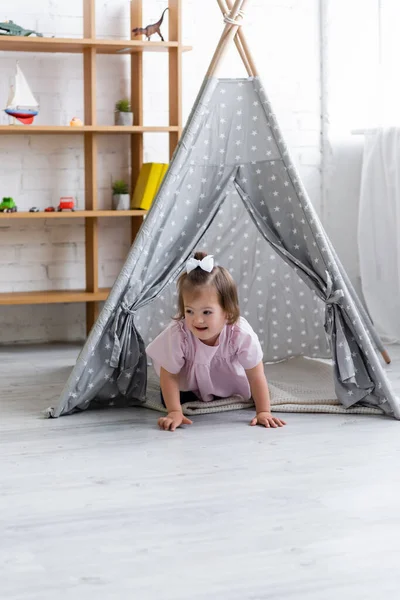 Garoto feliz com síndrome de down rastejando perto de tipi — Fotografia de Stock