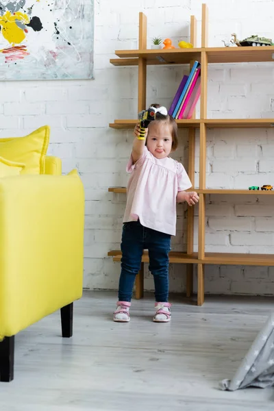 Kind mit Down-Syndrom hält Spielzeugpistole im Spielzimmer — Stockfoto