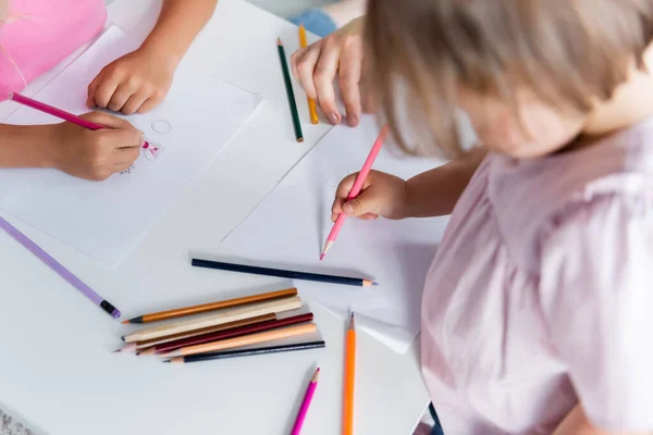 Vista ad alto angolo di bambini che disegnano vicino all'insegnante d'asilo — Foto stock