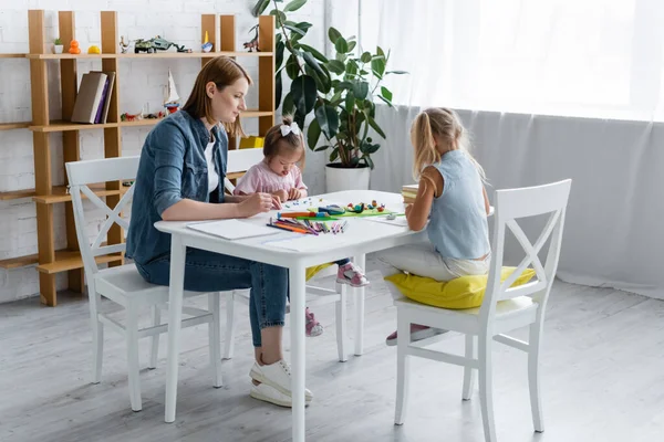 Kindergarten teacher molding plasticine with disabled child and preschooler girl — Stock Photo