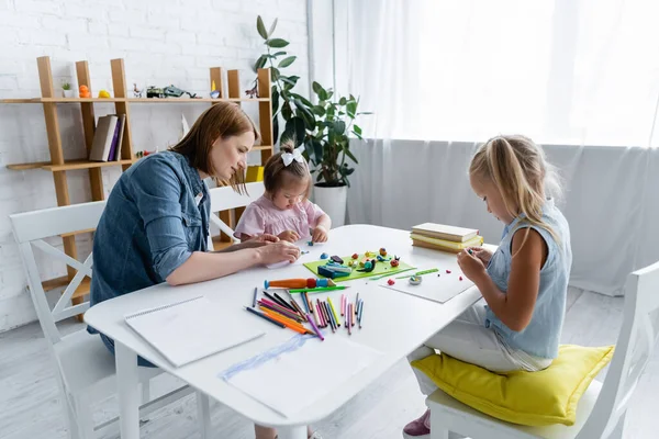 Scuola materna insegnante stampaggio plastilina con bambino disabile e bambino in età prescolare in sala giochi — Foto stock