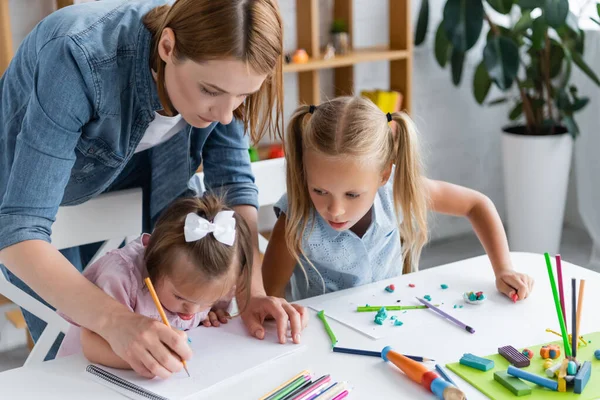 Teacher assisting disabled child with down syndrome drawing in private kindergarten — Stock Photo