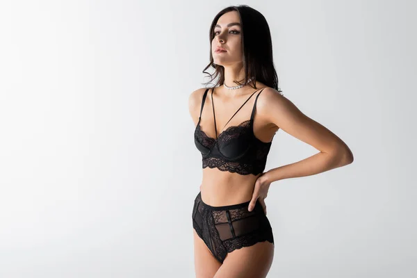 Brunette jeune femme en lingerie noire sexy posant avec la main sur la hanche isolé sur blanc — Photo de stock