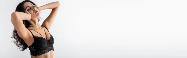 Giovane donna vincere reggiseno di pizzo nero in posa con gli occhi chiusi isolati su bianco, banner — Stock Photo