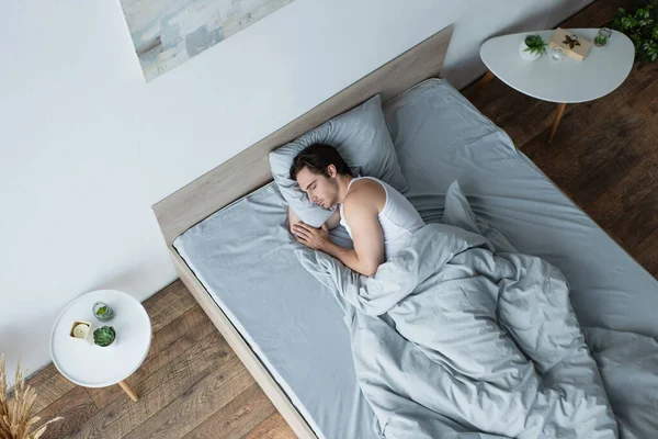 Vista ad alto angolo del giovane che dorme sotto la coperta blu — Foto stock