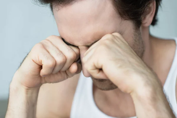 Jeune homme frottant les yeux avec les poings le matin — Photo de stock