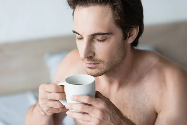Молодий брюнетка людина насолоджується ранковою кавою з закритими очима — стокове фото
