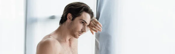 Brunette, shirtless man looking through window in morning, banner — Stock Photo