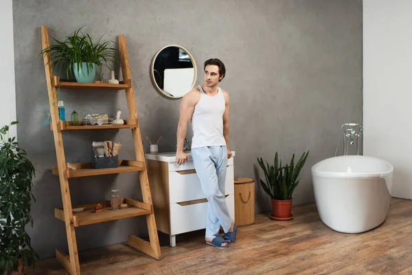 Ganzkörperansicht eines jungen Mannes, der in der Nähe eines Waschbeckens im modernen Badezimmer steht — Stockfoto
