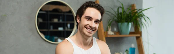 Happy brunette man looking at camera in bathroom, banner — Stock Photo