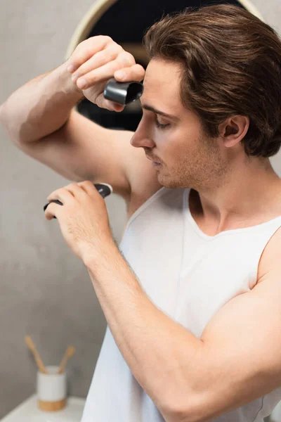 Young man using antiperspirant stick on armpit — Stock Photo