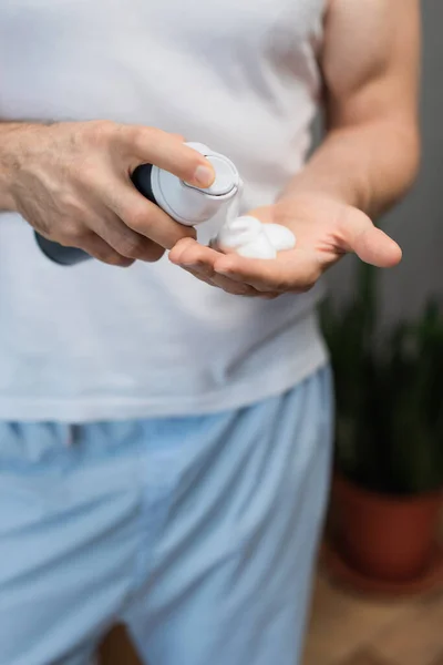 Vista recortada del hombre aplicar espuma de afeitar en la mano en el baño - foto de stock