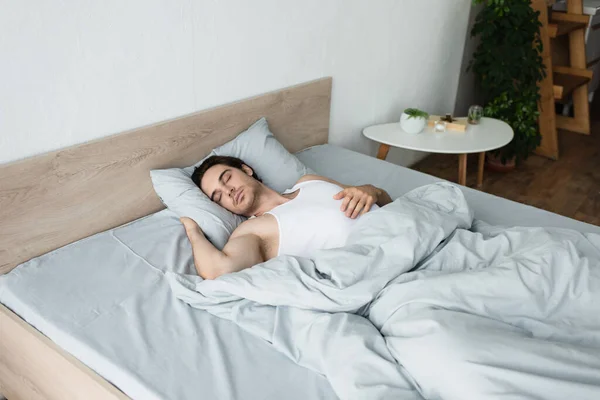 Молодой человек, спящий утром на синем постельном белье — стоковое фото