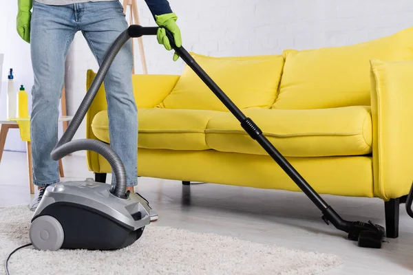 Cropped view of man vacuuming floor near couch — Stock Photo