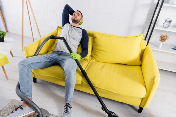 Vista de ángulo alto del hombre cansado en guantes de goma que sostienen la aspiradora - foto de stock