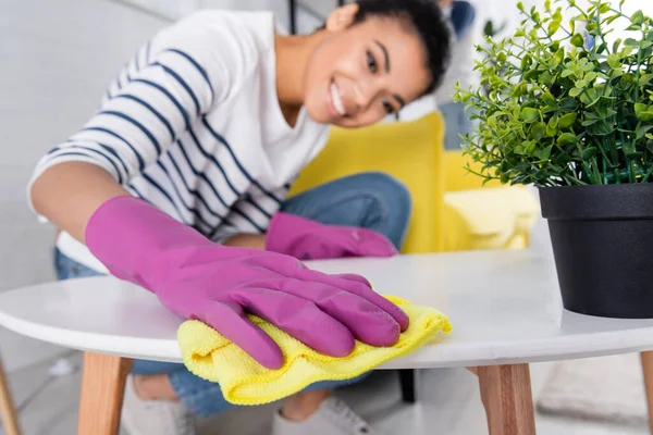 Rag in mano di donna afroamericana sorridente pulizia tavolino — Foto stock