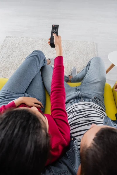 Overhead view of african american woman holding remote controller near boyfriend — Stock Photo