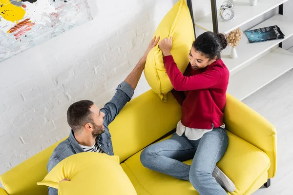 Overhead view of multiethnic couple fighting with pillows — Stock Photo