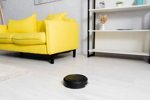 Robotic vacuum cleaner near carpet and couch — Stock Photo