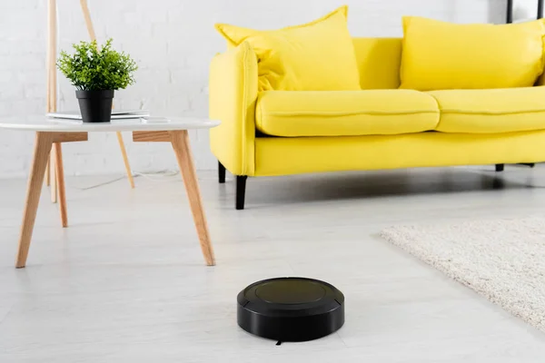 Robotic vacuum cleaner on floor near coffee table in living room — Stock Photo