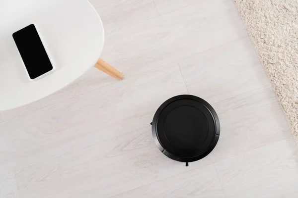 Top view of robotic vacuum cleaner and smartphone at home — Stock Photo