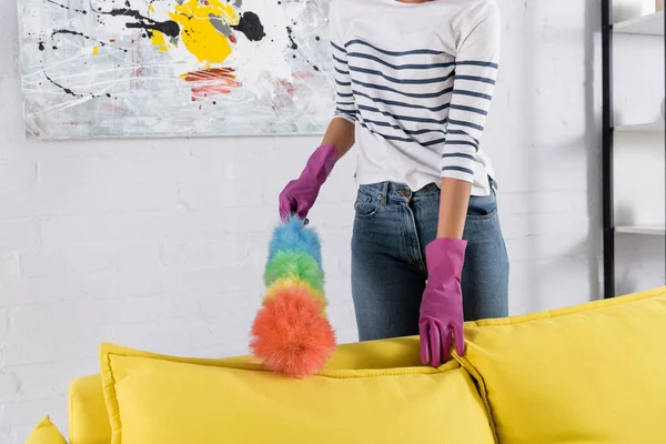 Vista ritagliata di donna pulizia divano con spazzola di polvere — Foto stock
