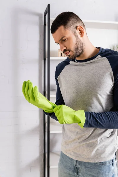 Giovane uomo che indossa guanti di gomma a casa — Foto stock