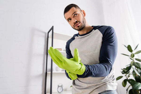Hombre usando guantes de goma durante la limpieza de la casa - foto de stock