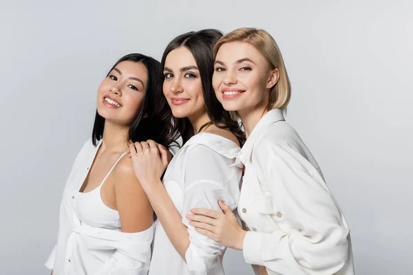 Modelos interraciales positivos sonriendo aislados en gris - foto de stock