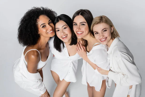 Vue grand angle de jeunes modèles multiethniques joyeux posant isolés sur gris — Photo de stock