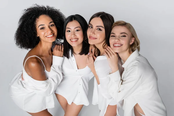 Vista de ángulo alto de modelos multiétnicos felices posando aislados en gris — Stock Photo