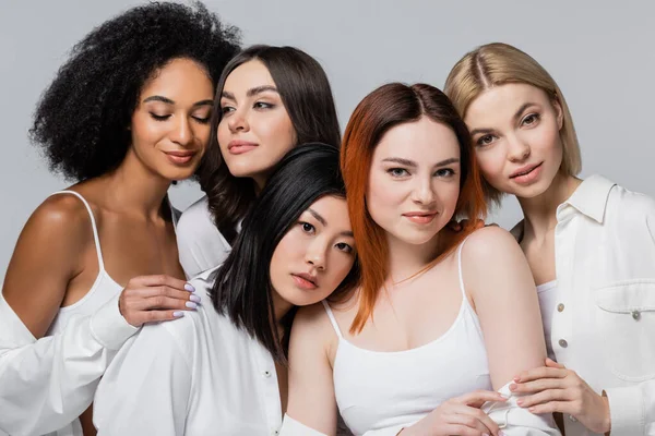 Modelos asiáticos y afroamericanos posando con mujeres jóvenes aisladas en gris - foto de stock