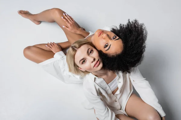 Von oben auf afrikanisch-amerikanische und blonde Models, die in die Kamera auf weiß schauen — Stockfoto