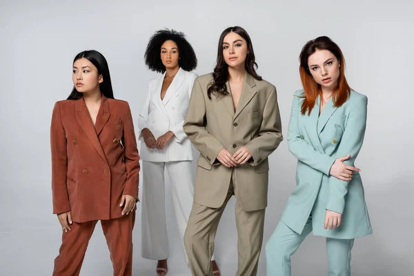 Gruppo multietnico di giovani modelli in abiti color pastello in posa sul grigio — Foto stock